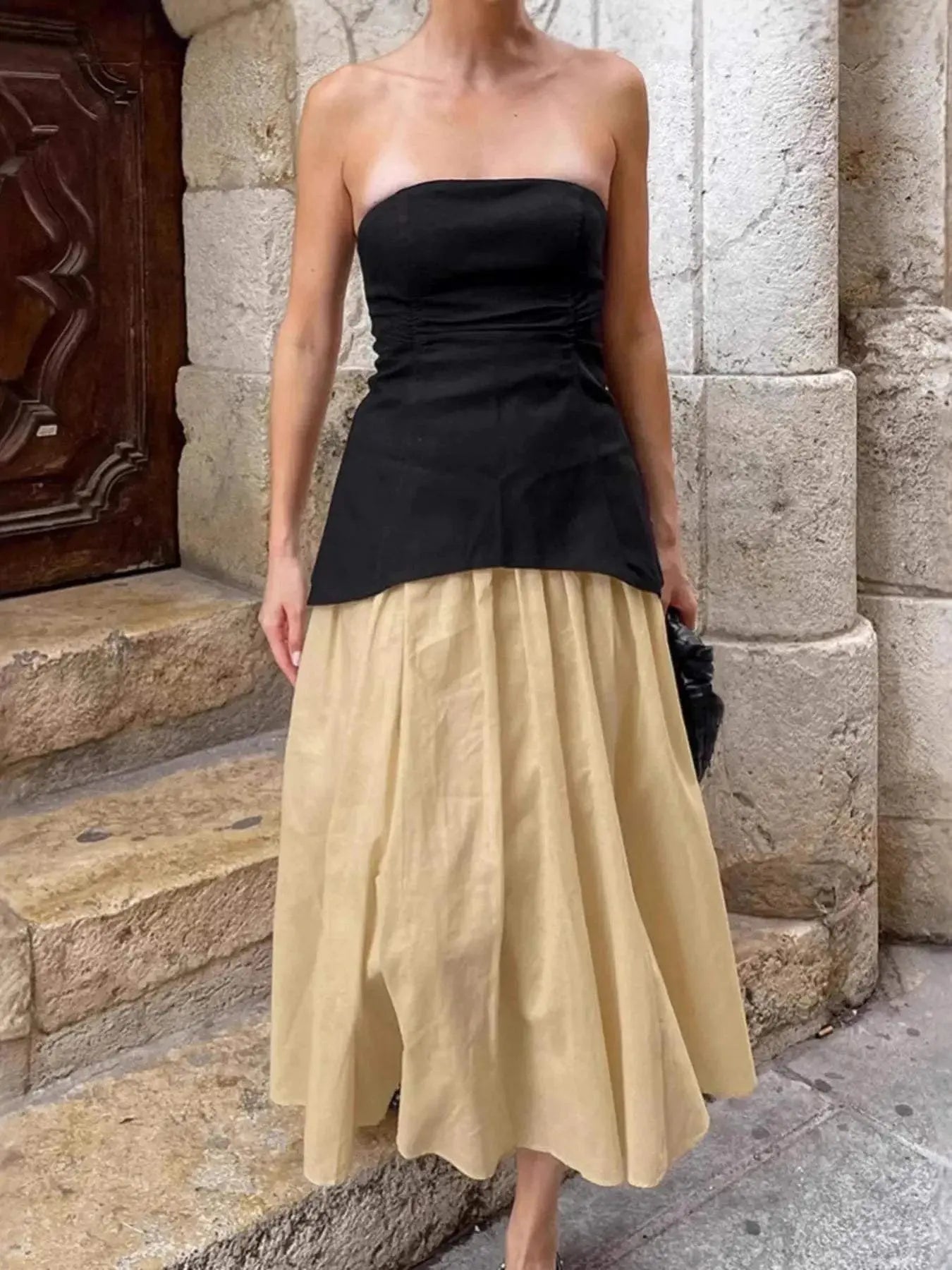 Woman wearing a black back zipper tube top paired with a beige midi skirt in a stylish outfit