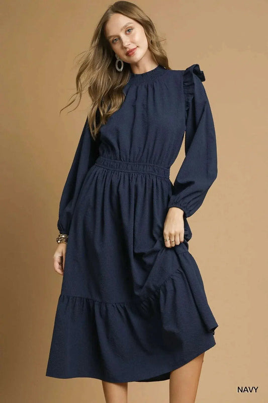 Woman wearing navy Umgee textured midi dress with ruffle shoulder and long sleeves