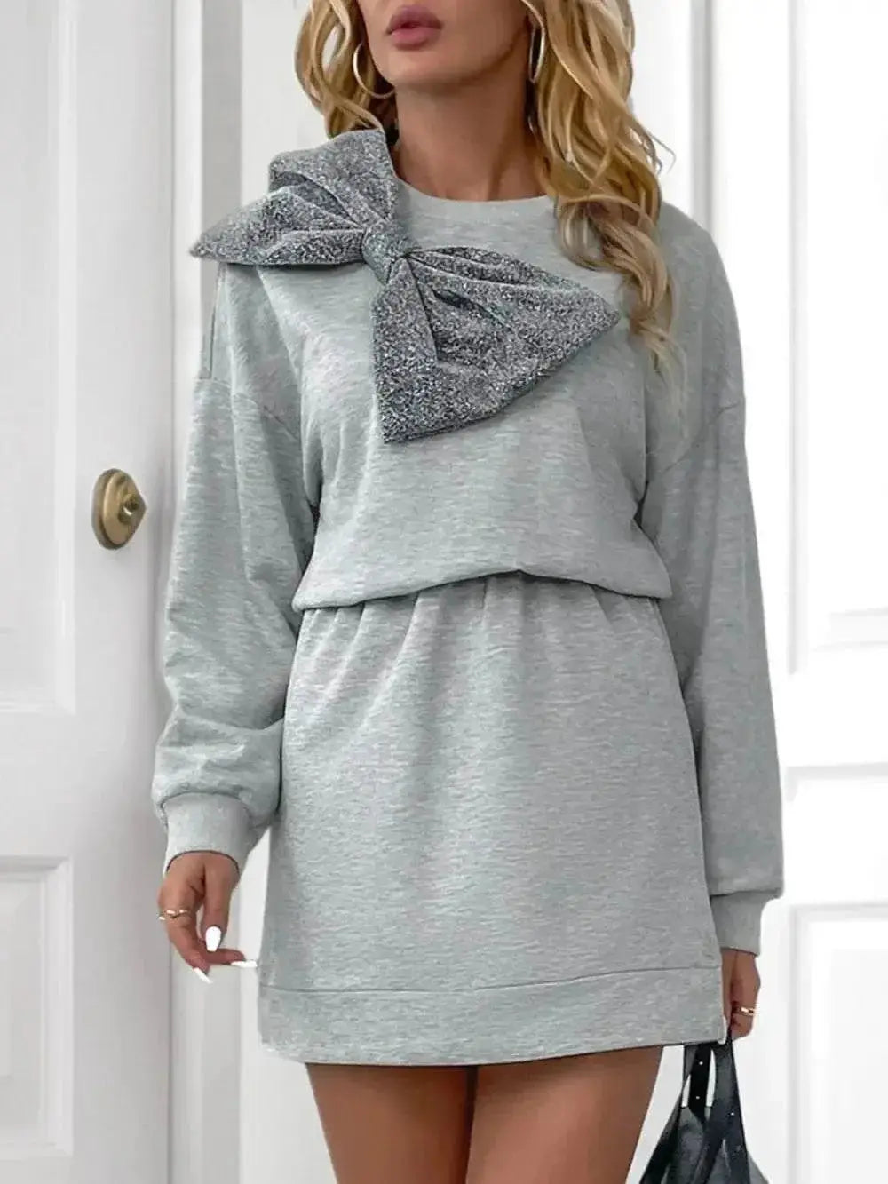 Woman wearing light grey Perfee Bow Mini Dress with dropped shoulder, long sleeves, and large bow detail on shoulder